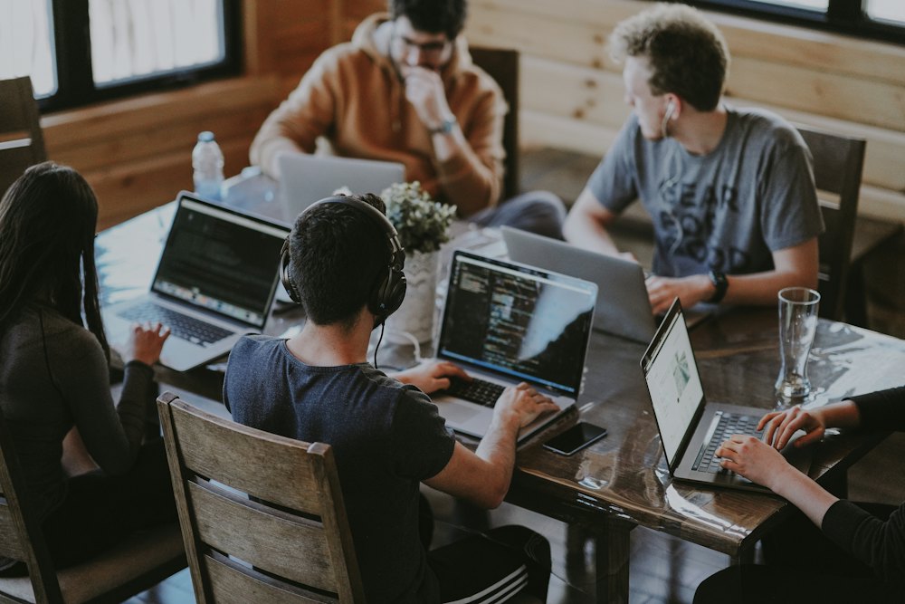 A small agency team working together around laptops at a shared desk